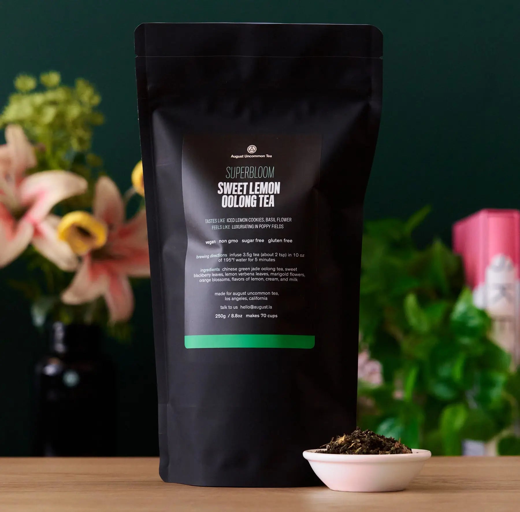 Black tea package with 'Superbloom' branding on a wooden surface with flowers in the background